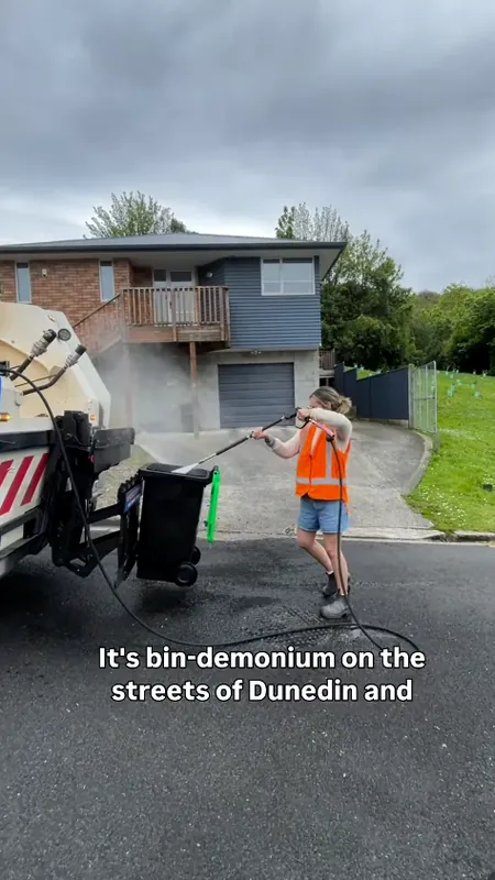 Bin Blast worker pressure-washing a wheelie bin on a Dunedin street